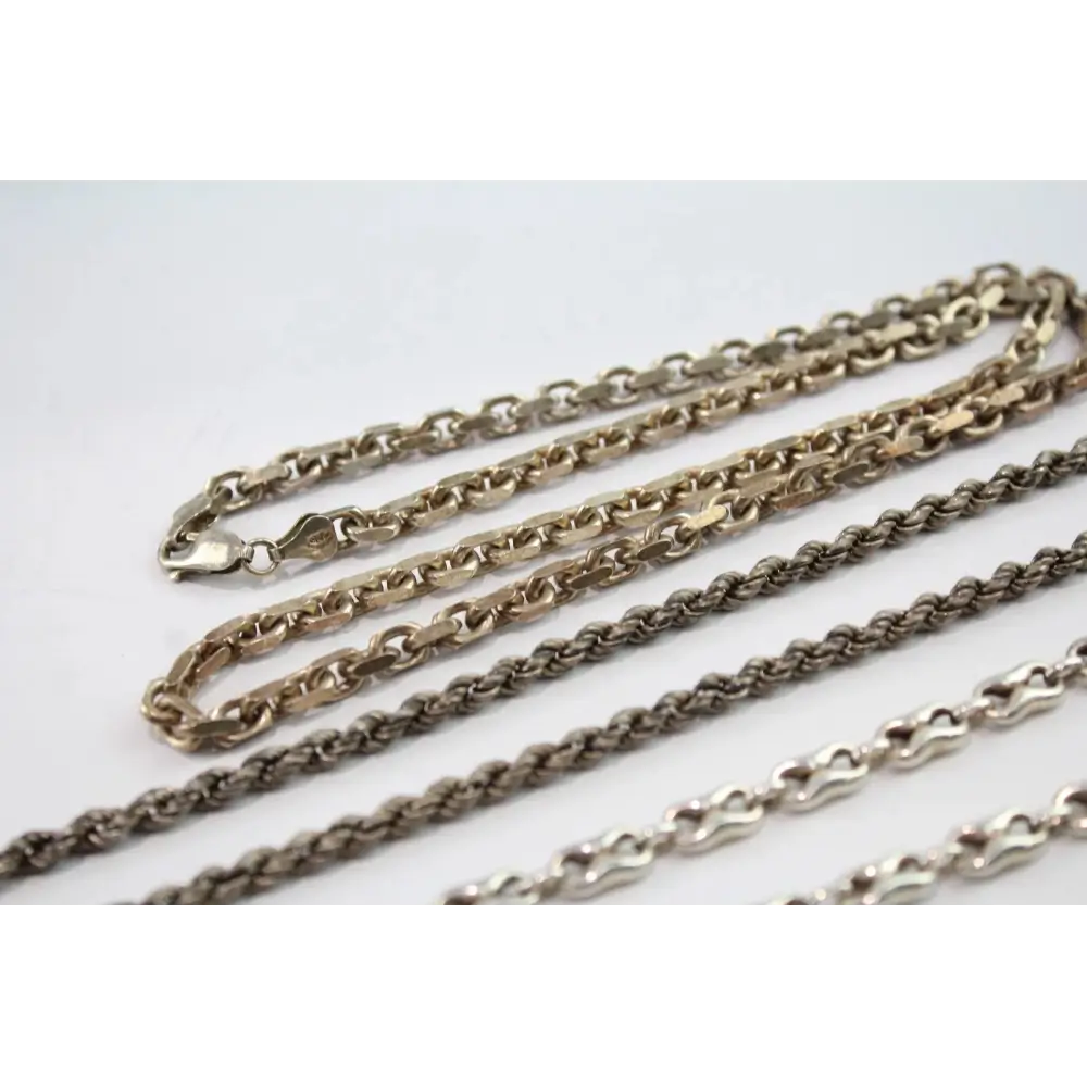 Gold, silver, and bronze chain necklaces on a white background