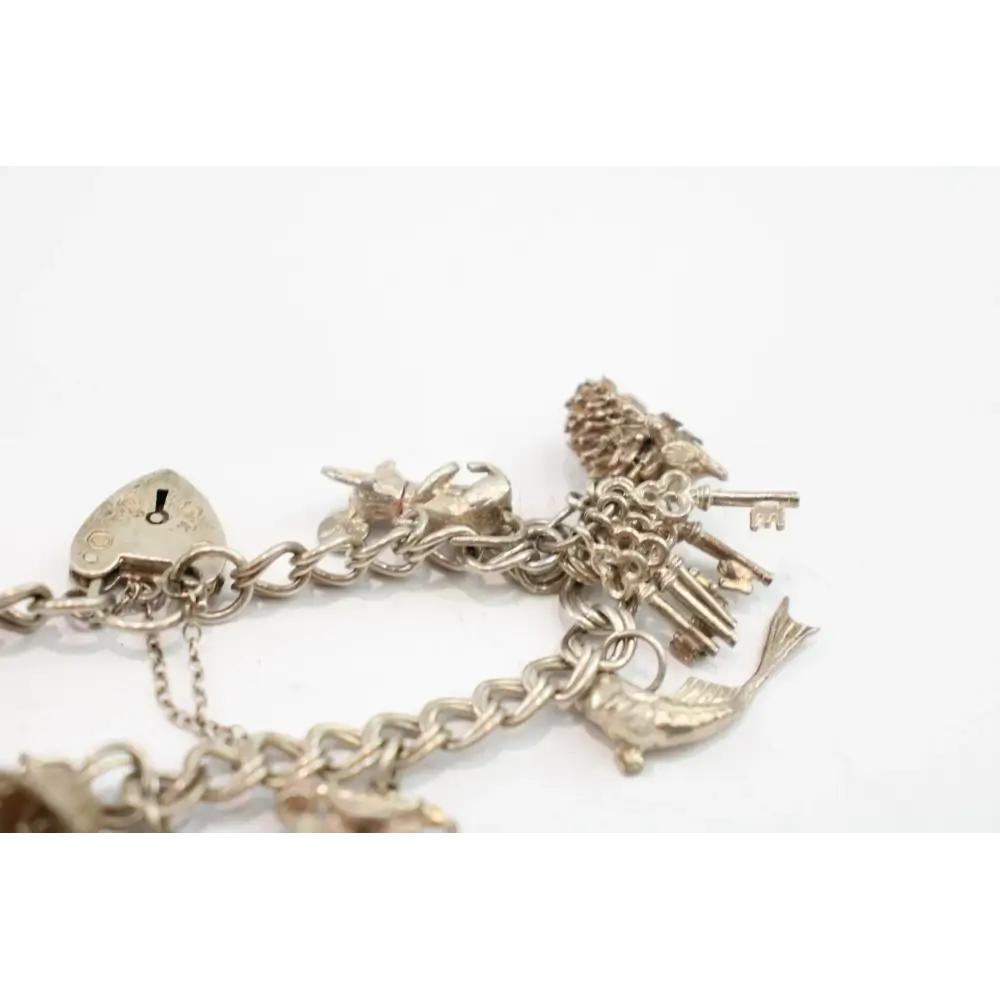 Silver charm bracelet with various charms on a white background