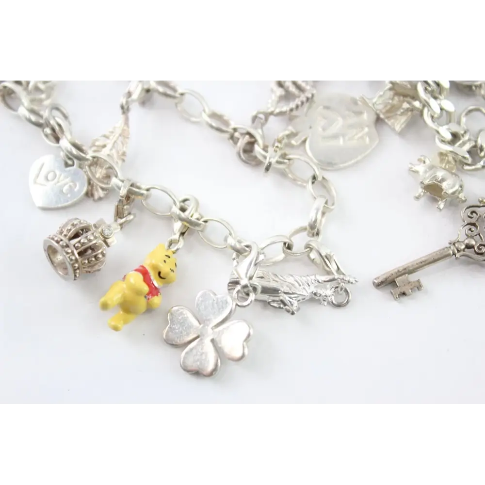 Silver charm bracelet with various charms including a yellow bear, clover, and key
