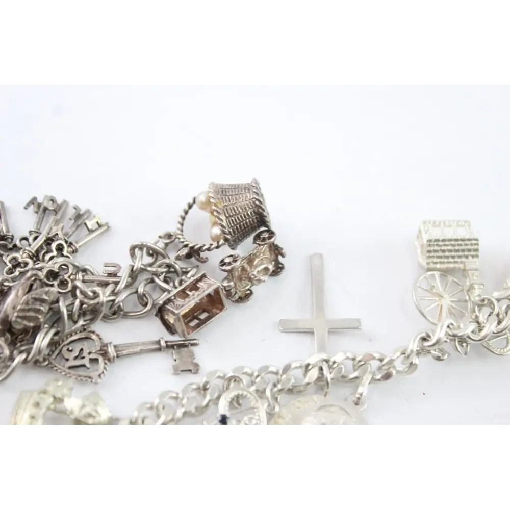 Silver charm bracelet with various charms on a white background