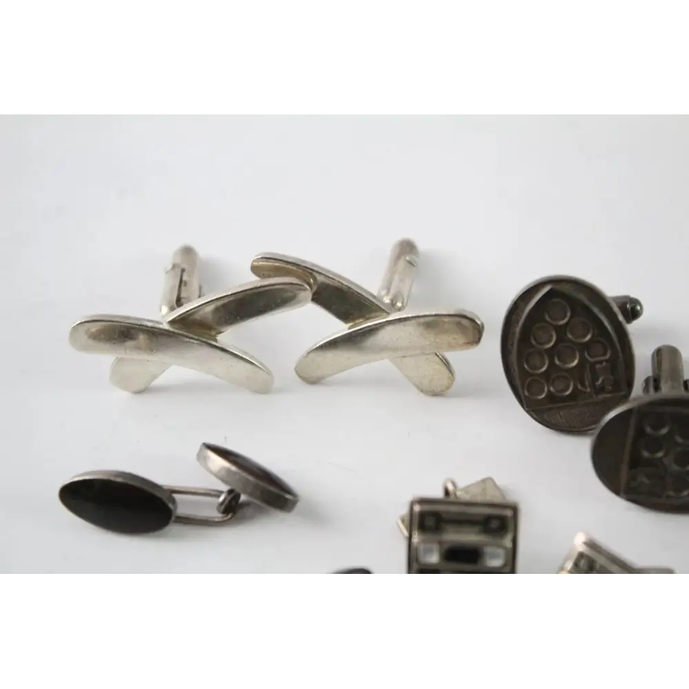 Collection of silver and black cufflinks on a white background