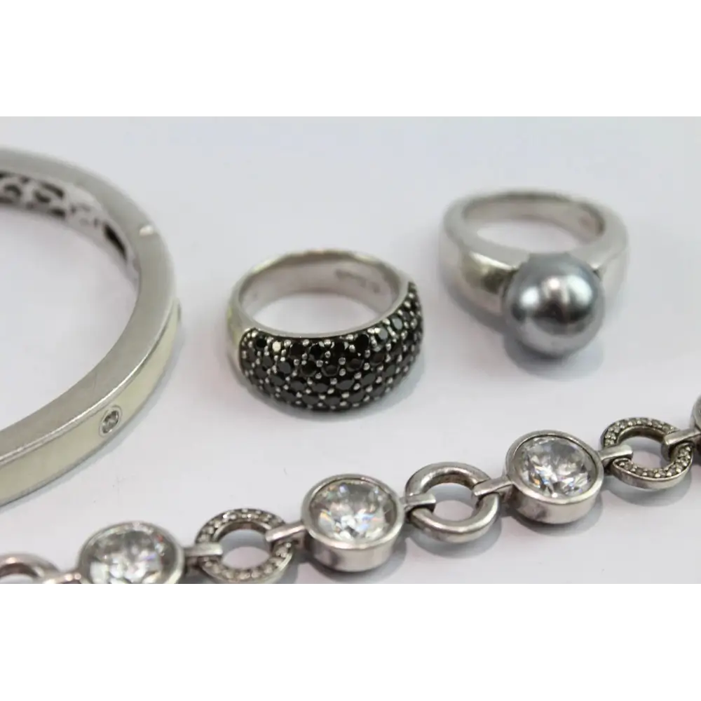 Collection of silver rings and a bracelet on a white background