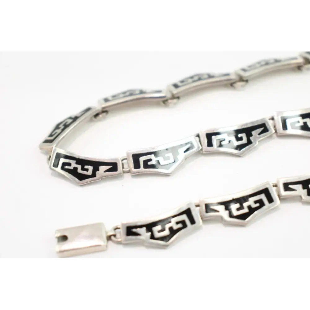 Silver bracelet with black geometric patterns on a white background