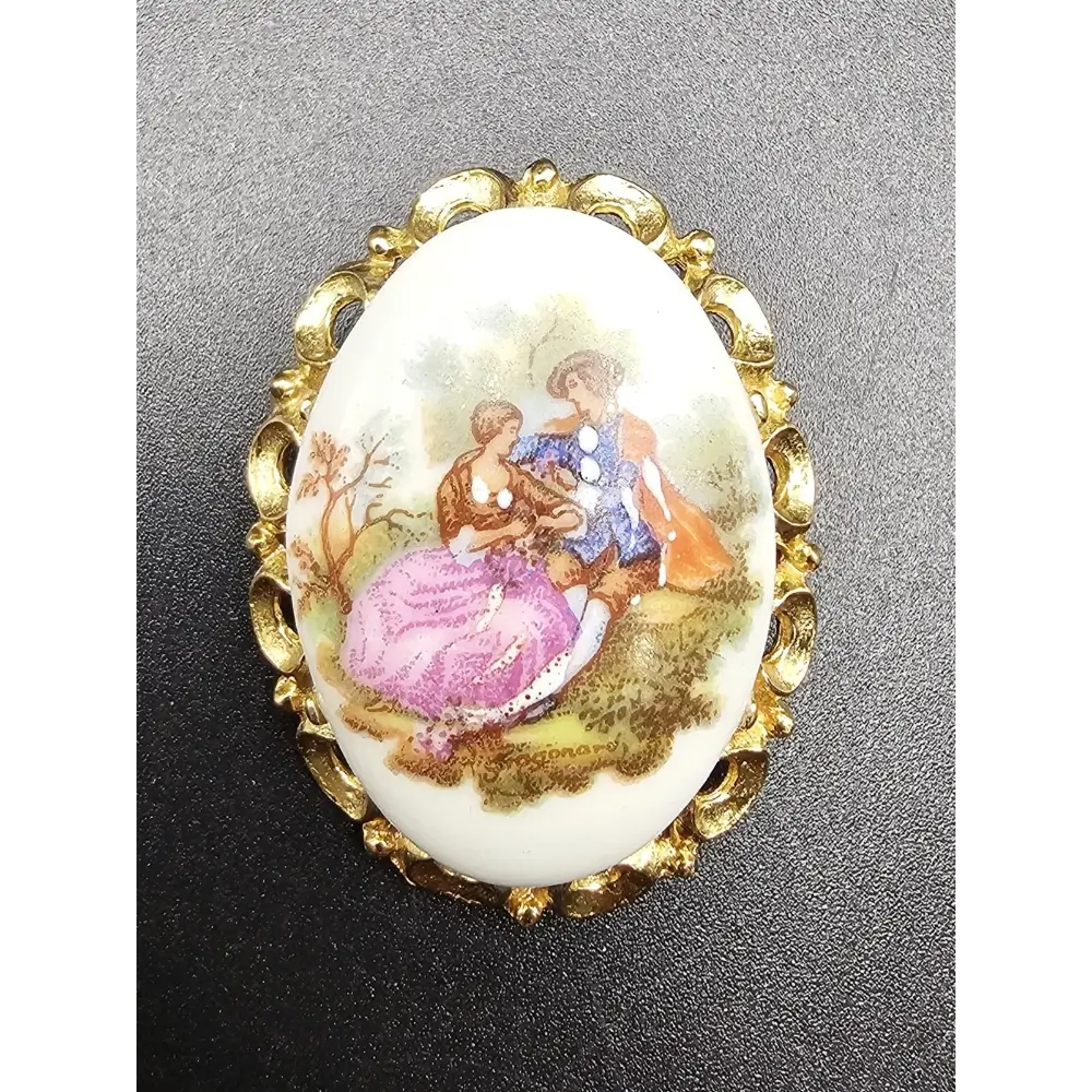Decorative brooch with a gold frame and painted scene