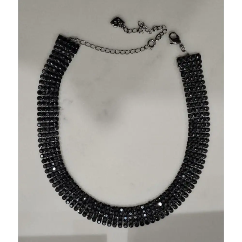 Black beaded necklace on a white marble surface