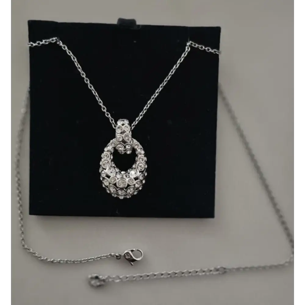 Silver necklace with a heart-shaped pendant on a black display stand.