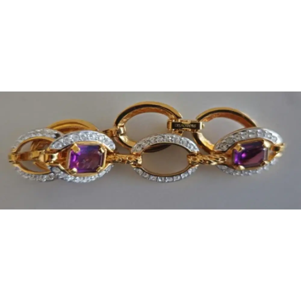 Gold and silver bracelet with purple gemstones on a gray background