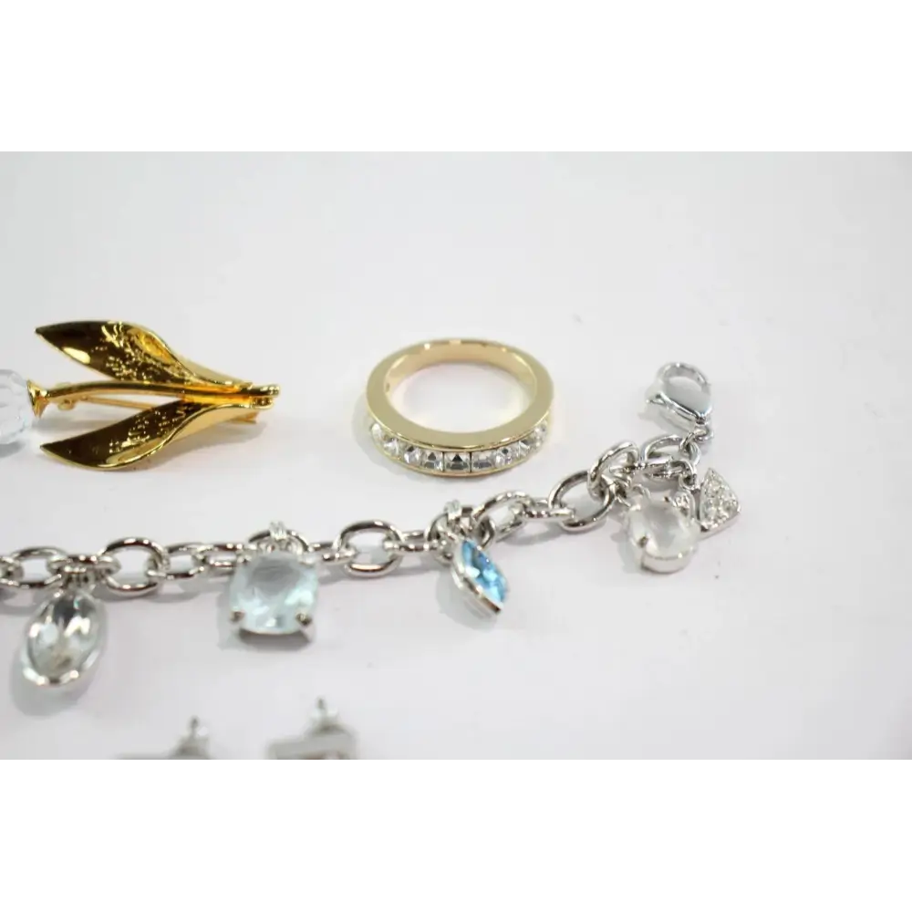 Jewelry items including a gold brooch, ring, and bracelet with charms on a white background