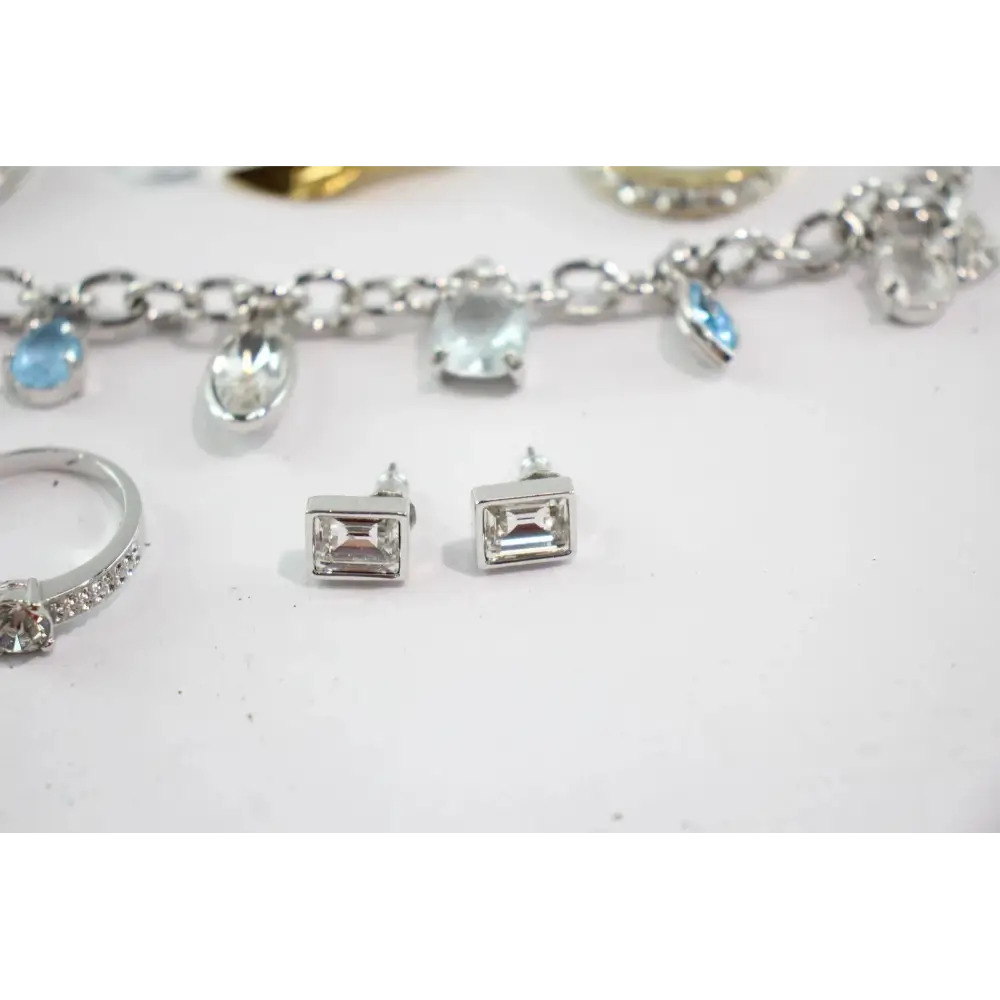Silver jewelry including earrings, a ring, and a bracelet with charms on a white background