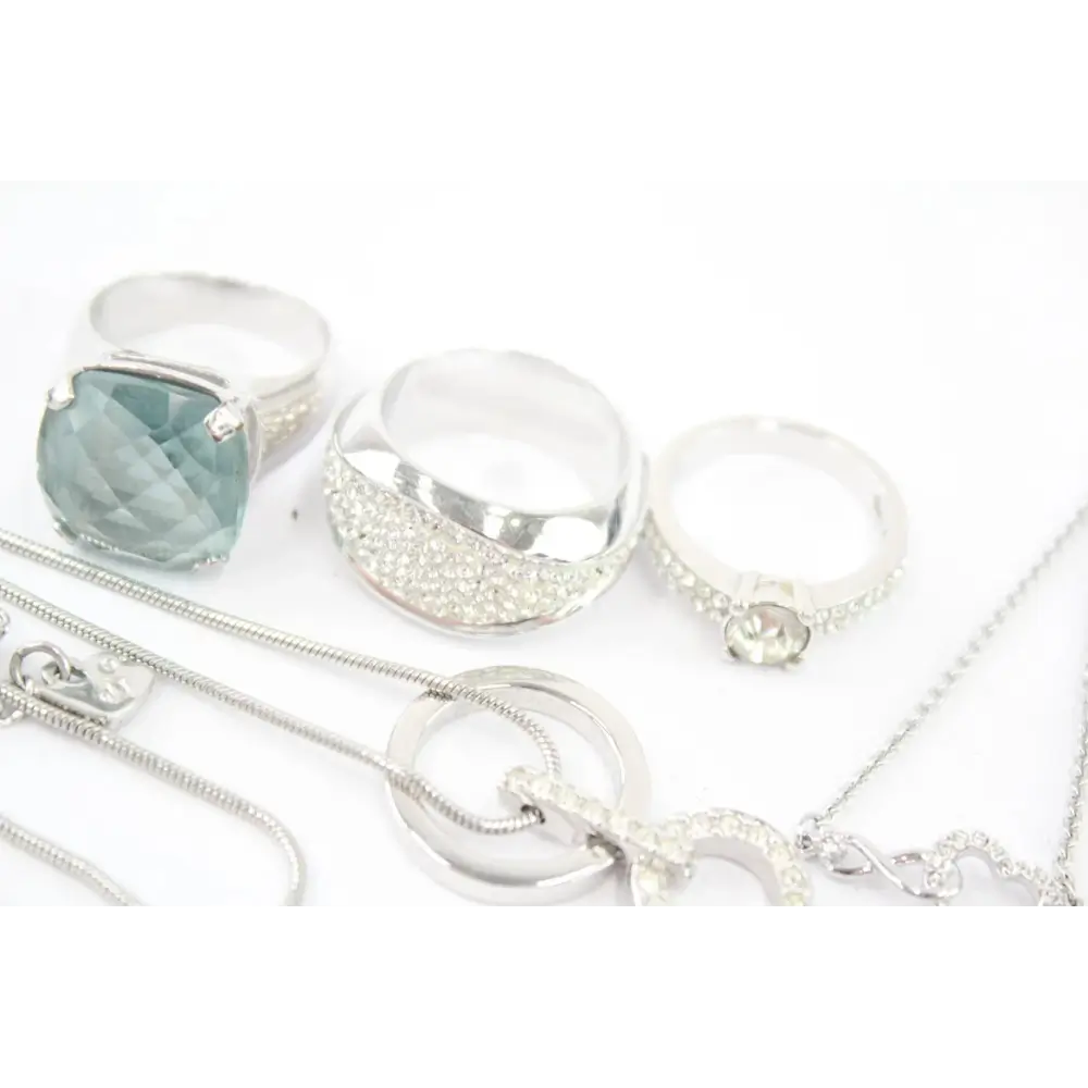 Collection of silver jewelry including rings and necklaces on a white background