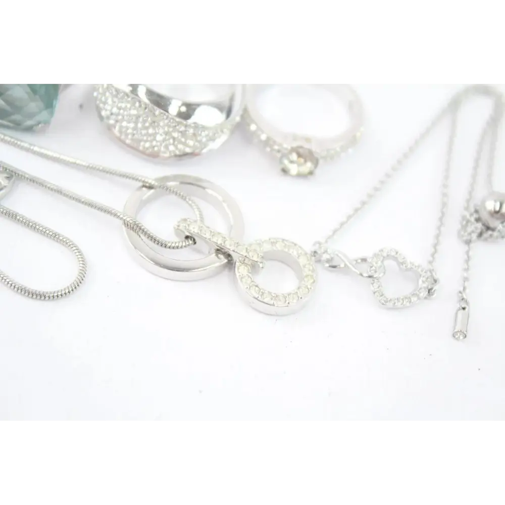 Silver jewelry including necklaces and bracelets on a white surface