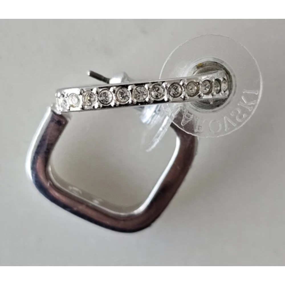 Silver earring with clear gemstones on a gray background