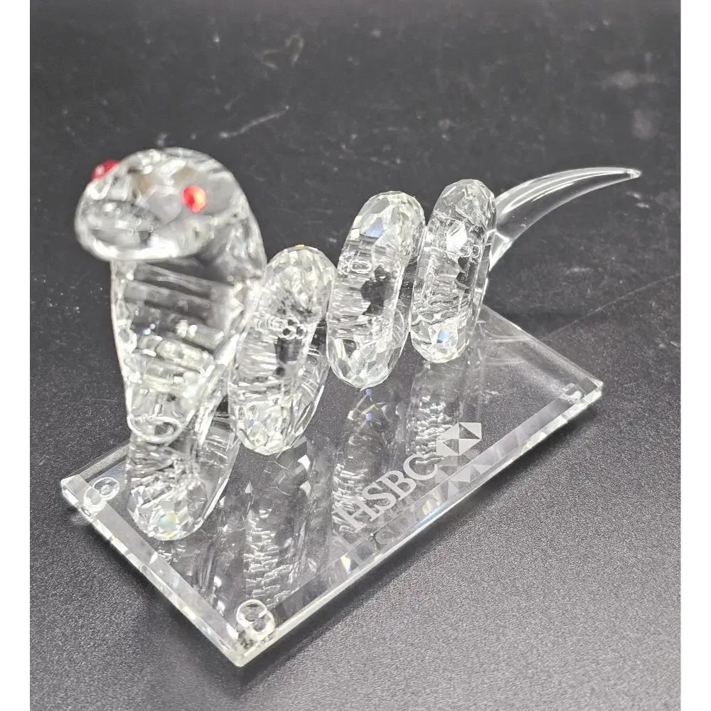 Crystal snake figurine on a clear base with ' HSBC' branding.
