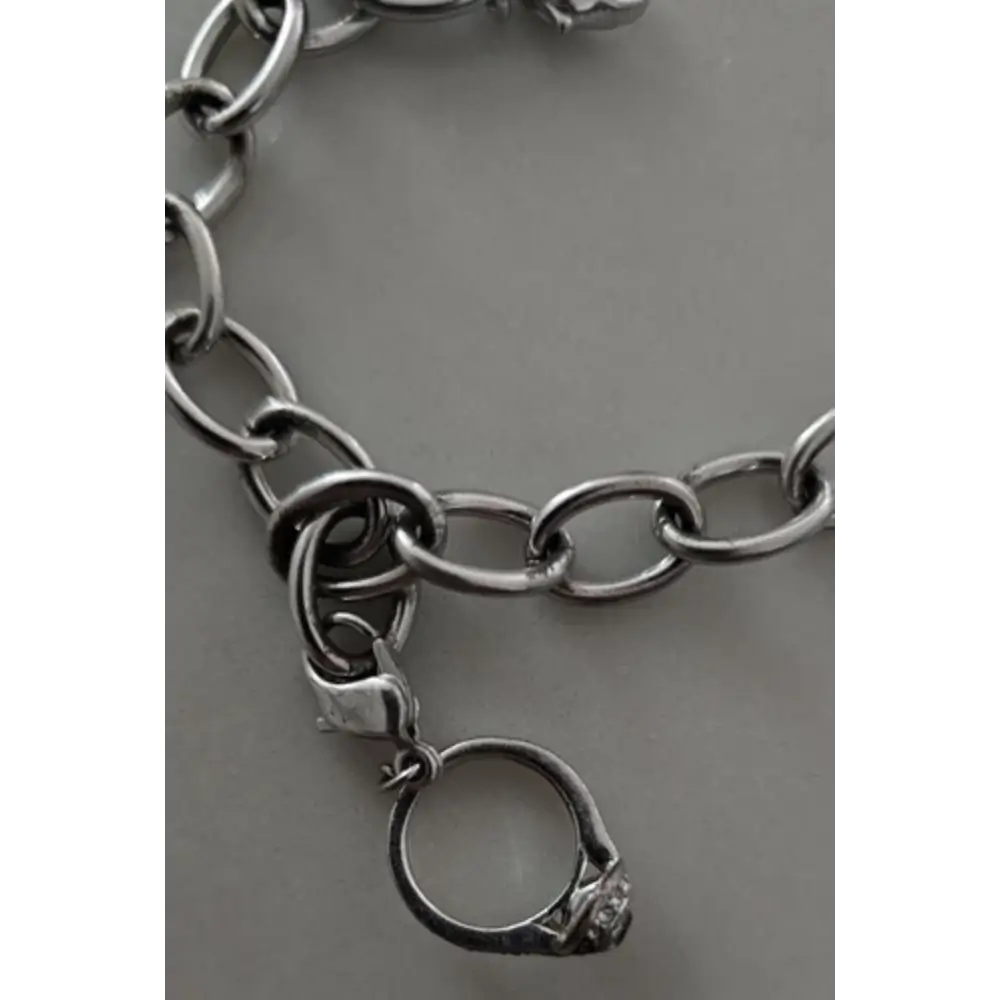 Silver chain bracelet with a ring charm on a gray background
