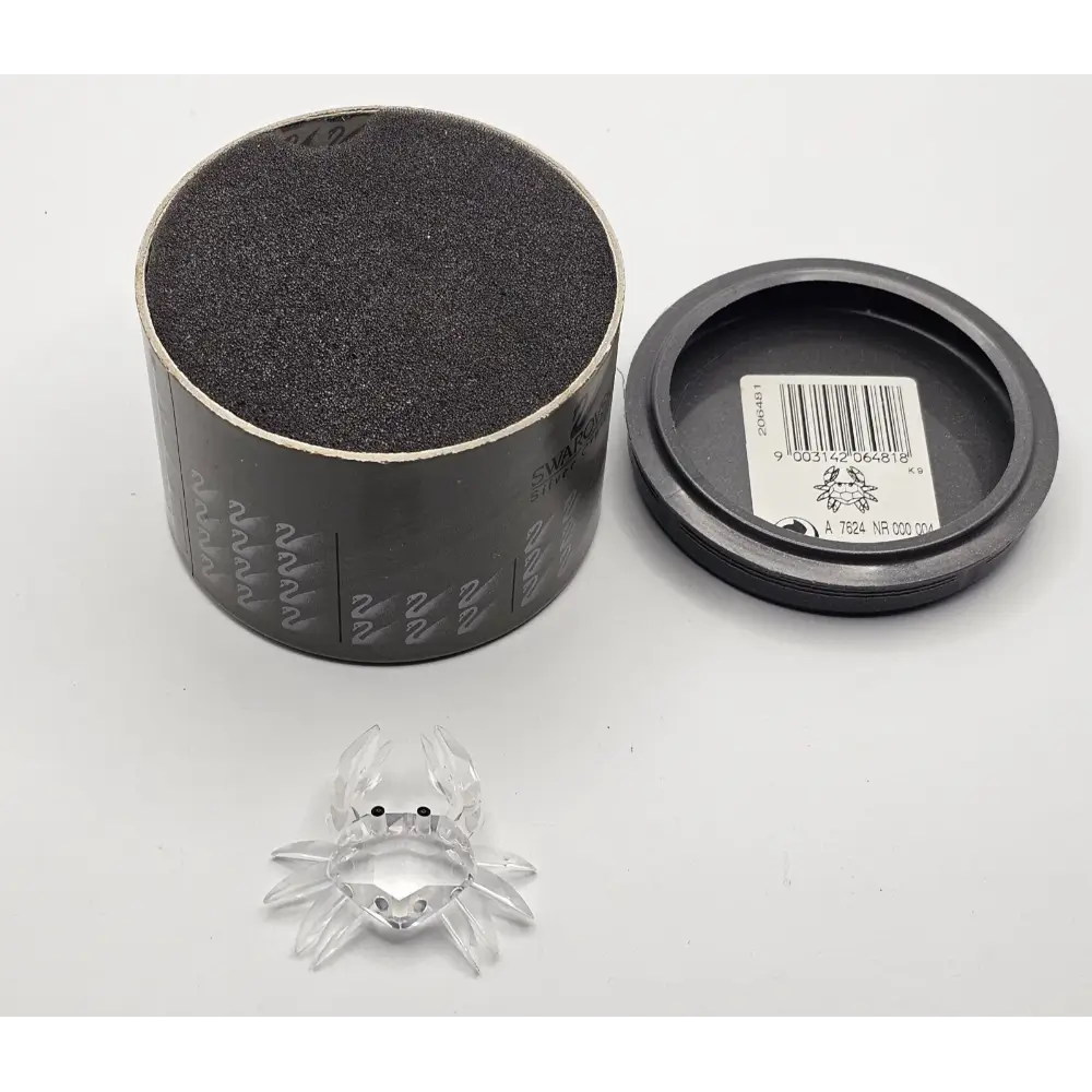 Clear glass spider figure in front of an open black container