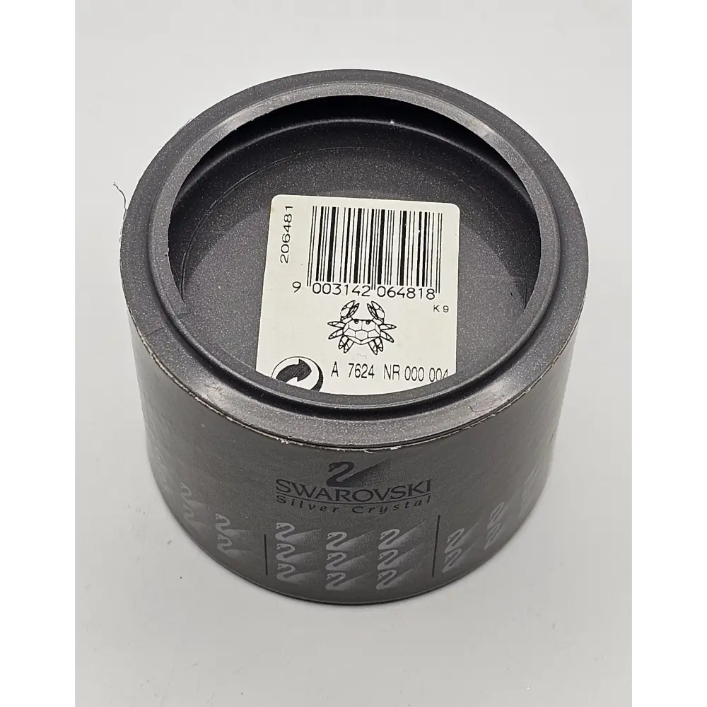 Gray metal component with a barcode label and Swarovski branding on a white background