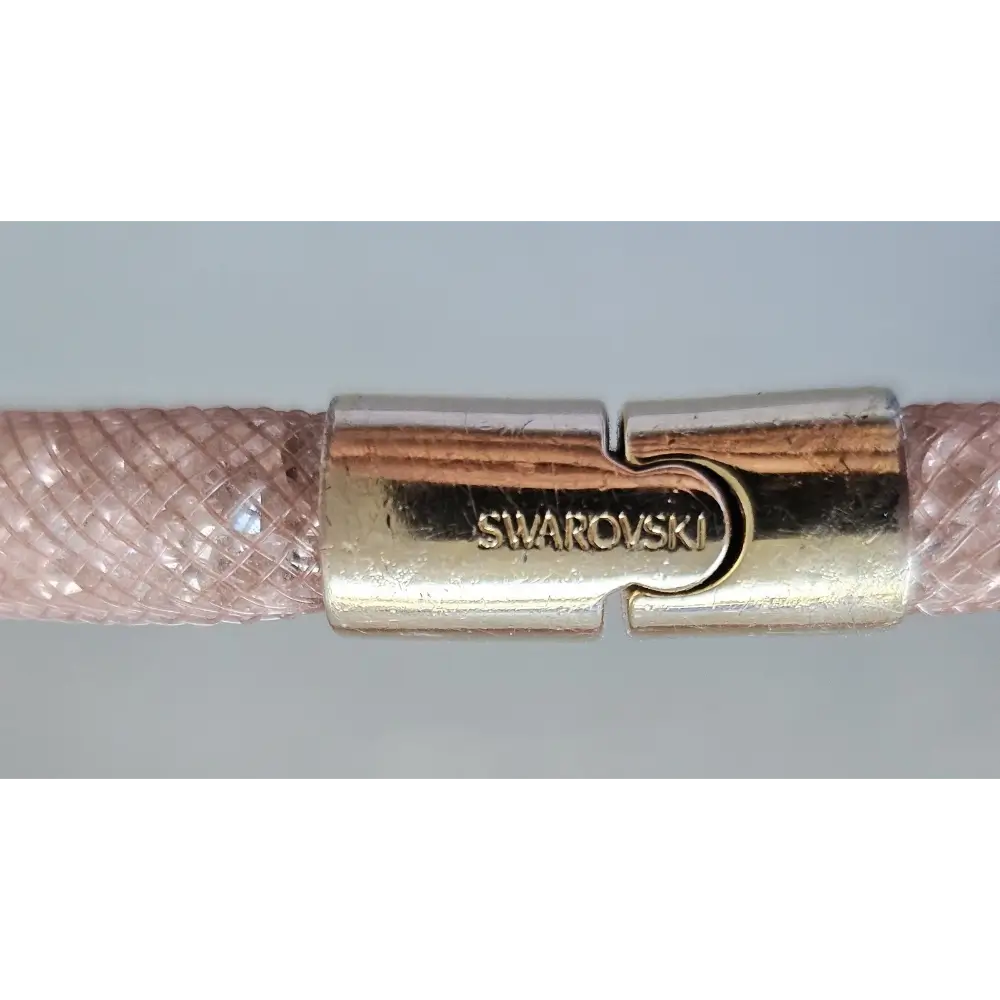 Close-up of a Swarovski clasp on a pink braided cord.
