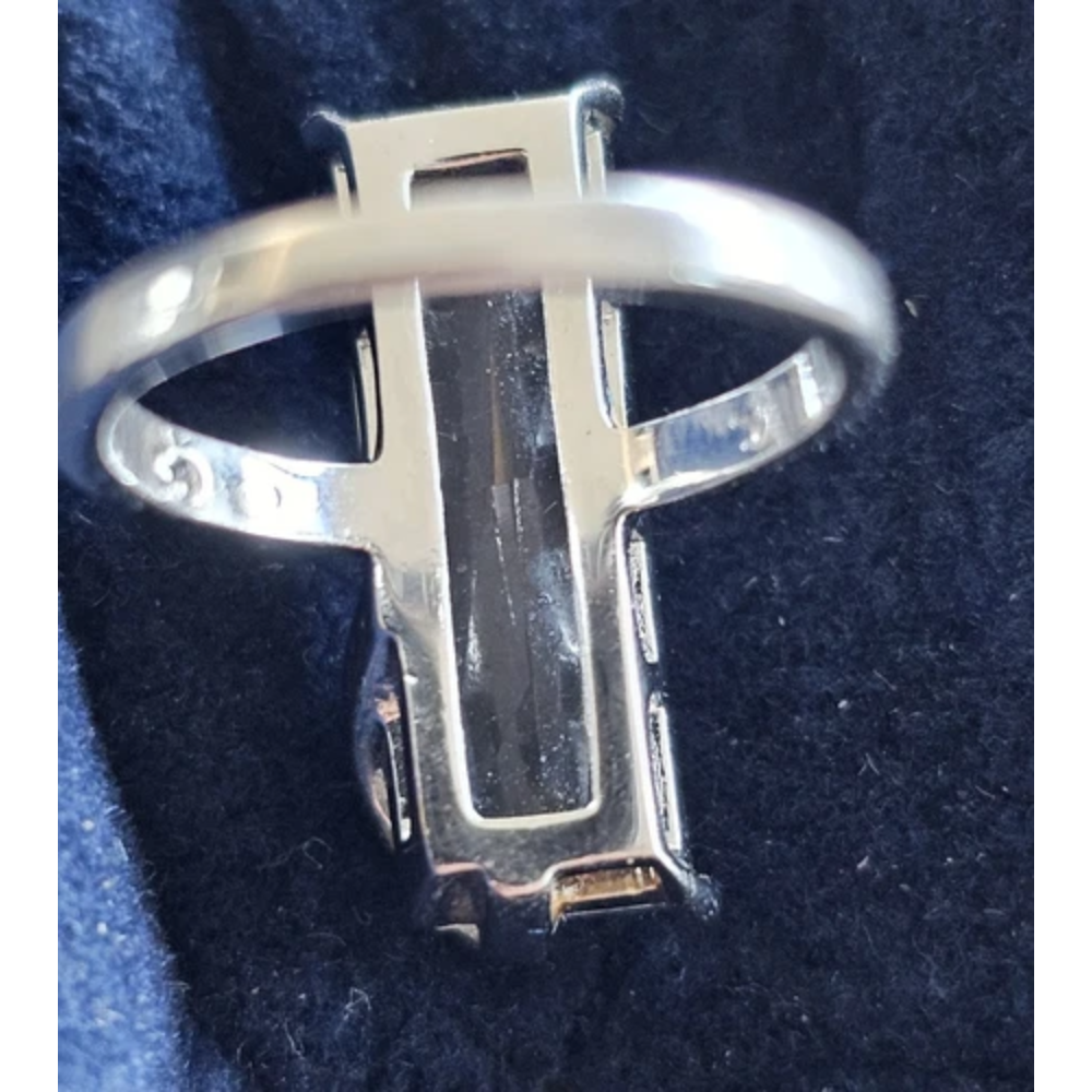Silver ring with a dollar sign design on a dark blue background