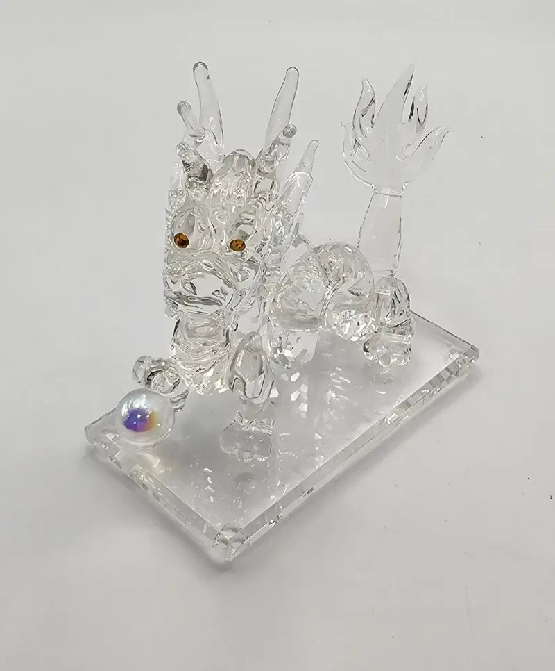 Crystal dragon figurine on a white base with a white background