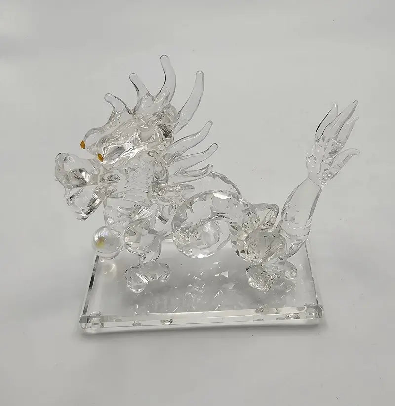 Clear glass dragon figurine on a square base against a white background