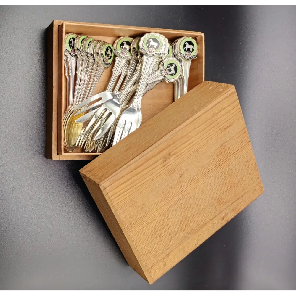 Set of silver spoons and forks in a wooden box on a gray background