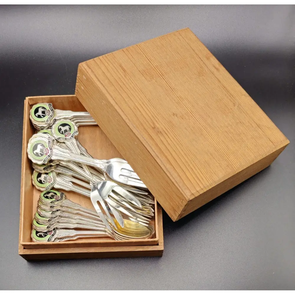Set of silver spoons in a wooden box on a gray background