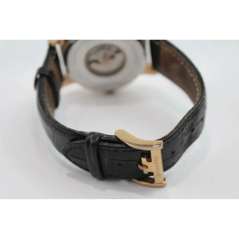 Black leather watch strap with gold buckle on a white background