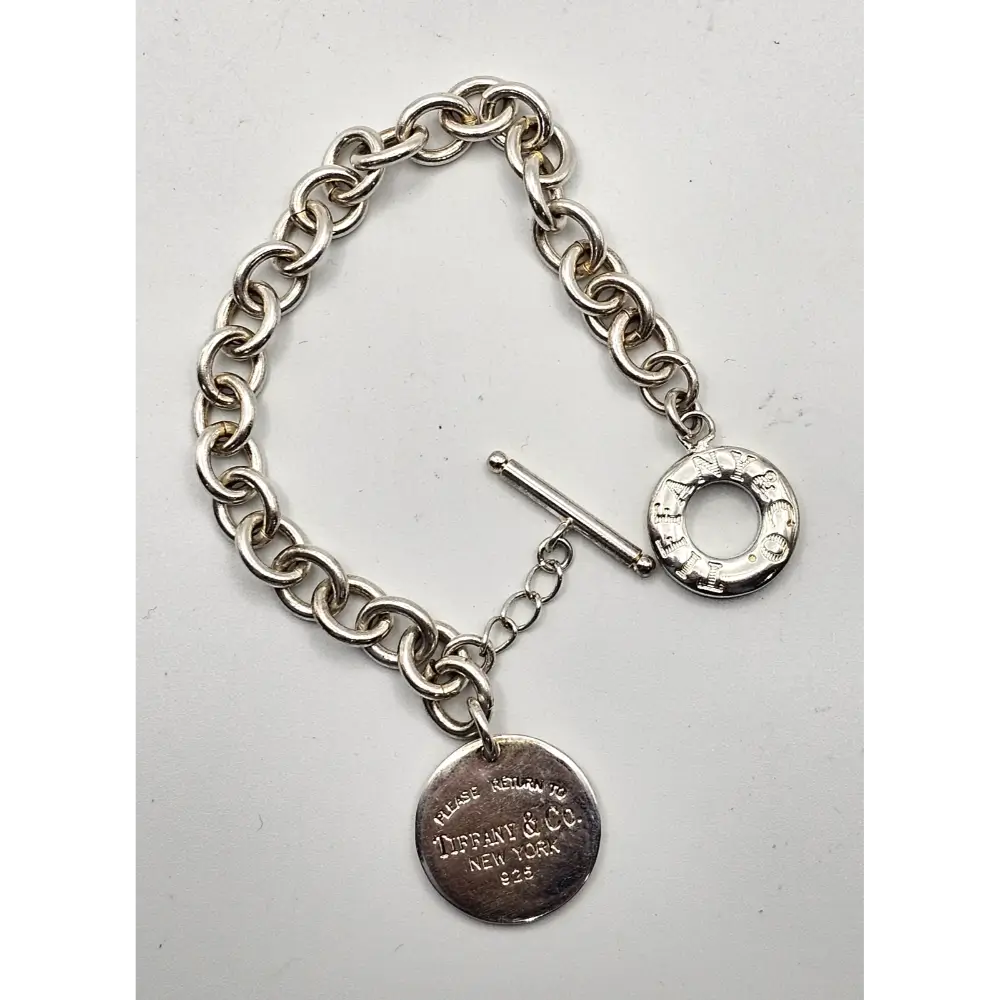 Silver bracelet with a tag on a light gray