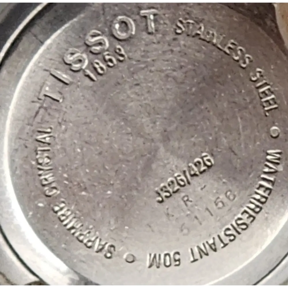 Close-up of Tissot watch caseback with branding and model details.