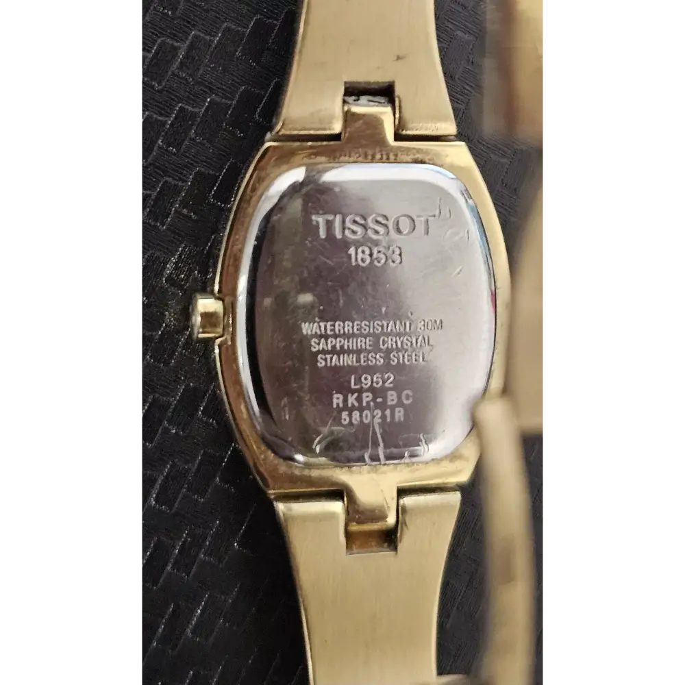 Gold Tissot watch on a textured black background