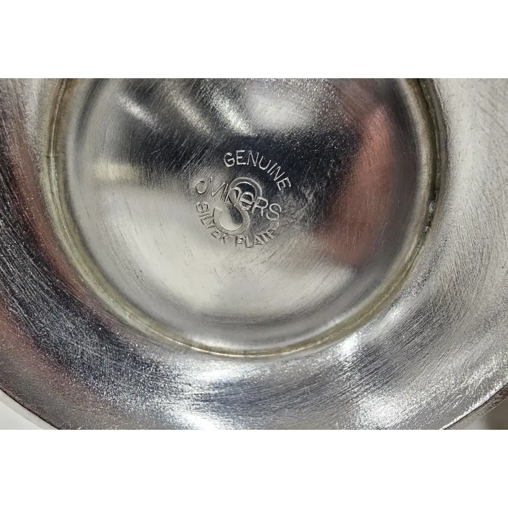 Close-up of a silver dish with 'Genuine Rogers' engraving on a white background