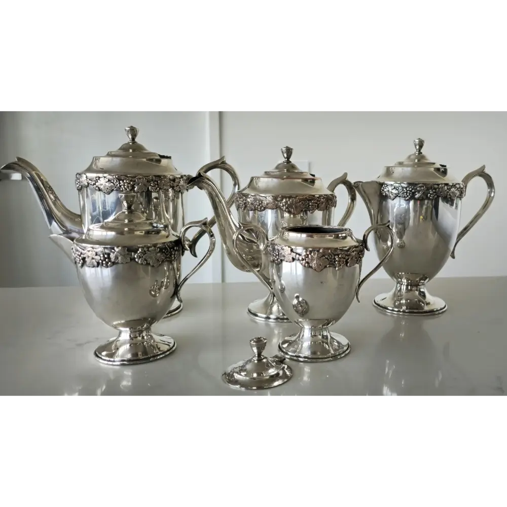 Silver tea set with ornate designs on a white surface