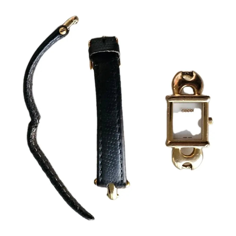 Black leather strap with gold hardware on a white background