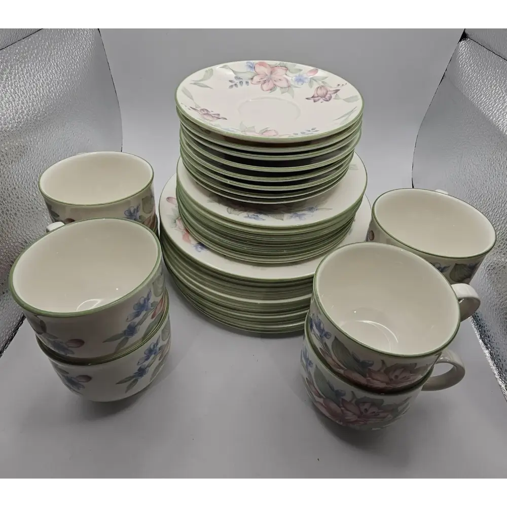Set of ceramic plates and cups with floral design on a gray surface