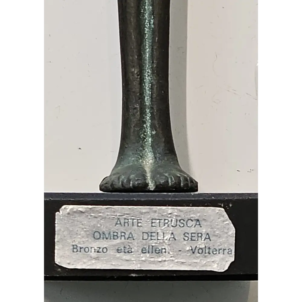 Bronze statue with a label indicating 'Arte Etrusca' on a white background