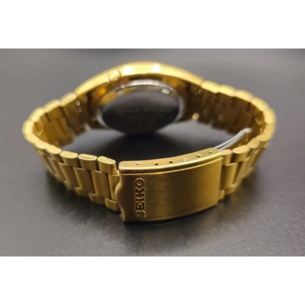 Gold watch with 'Seiko' branding on a dark surface
