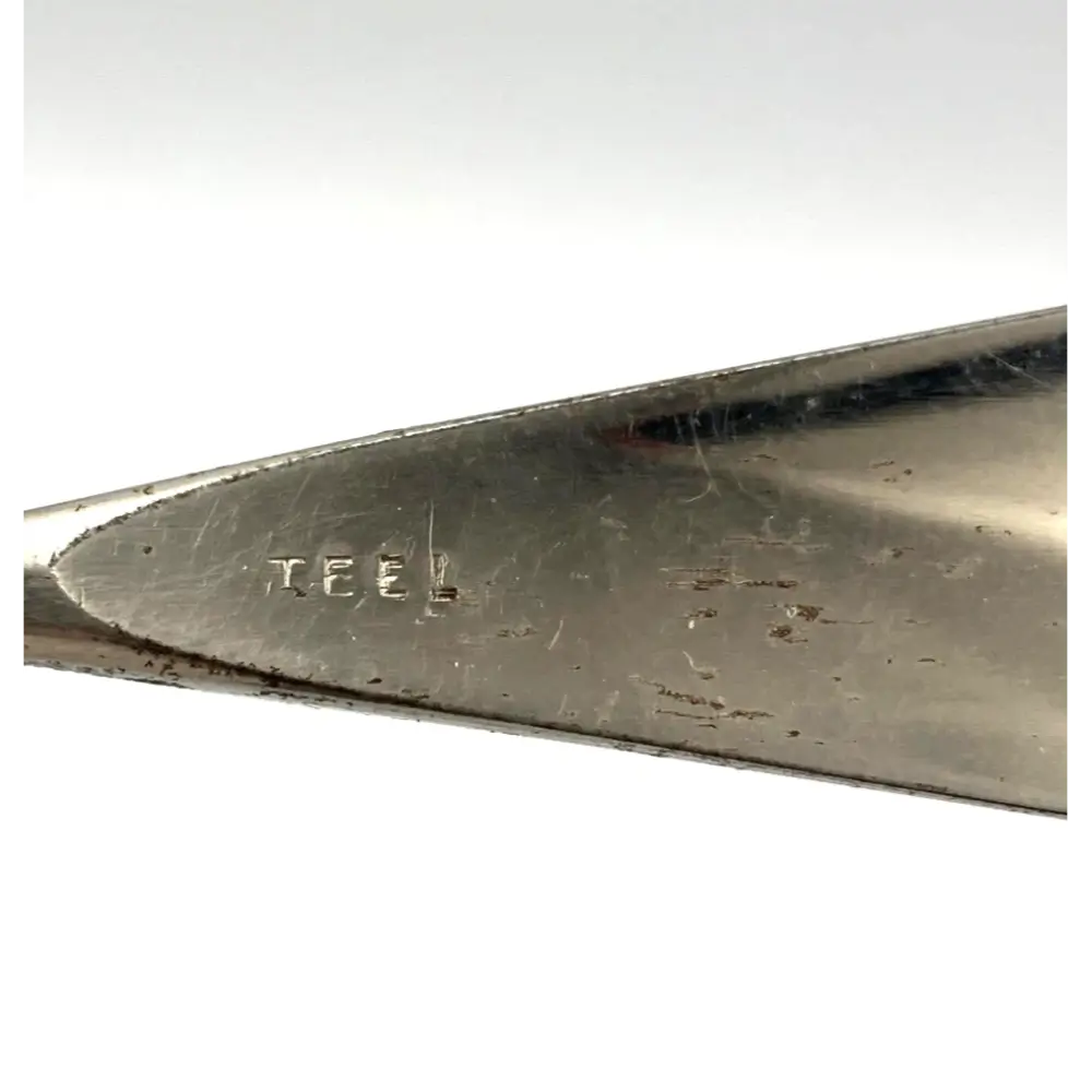 Close-up of a metal tool with 'TEEL' branding on a white background