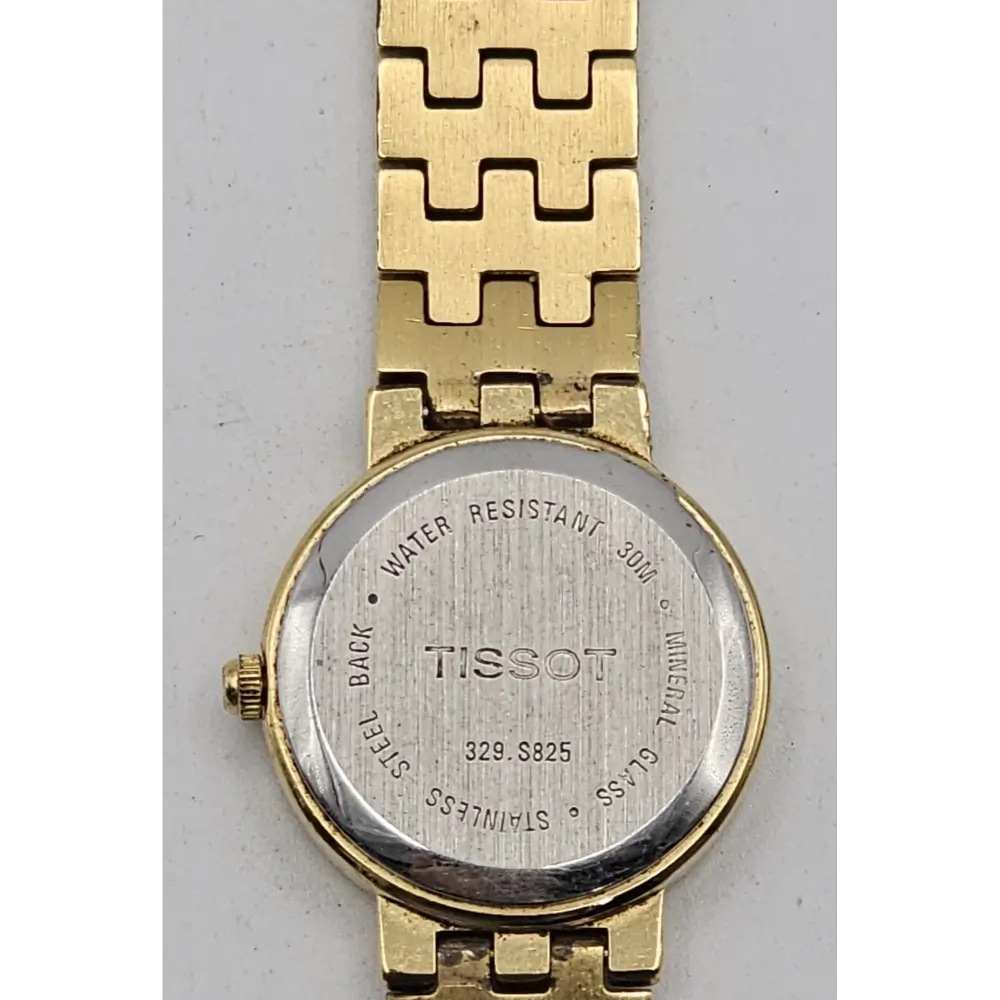 Gold watch with Tissot branding on a gray background