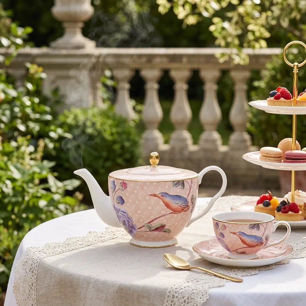 Elegant Wedgwood Paeonia Blush teapot with gold accents in a bright sunlit garden setting.
