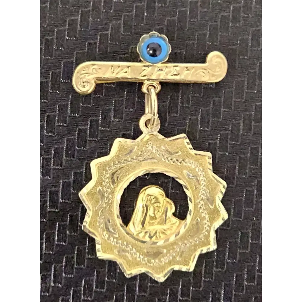 Gold pendant with a central figure on a black textured background