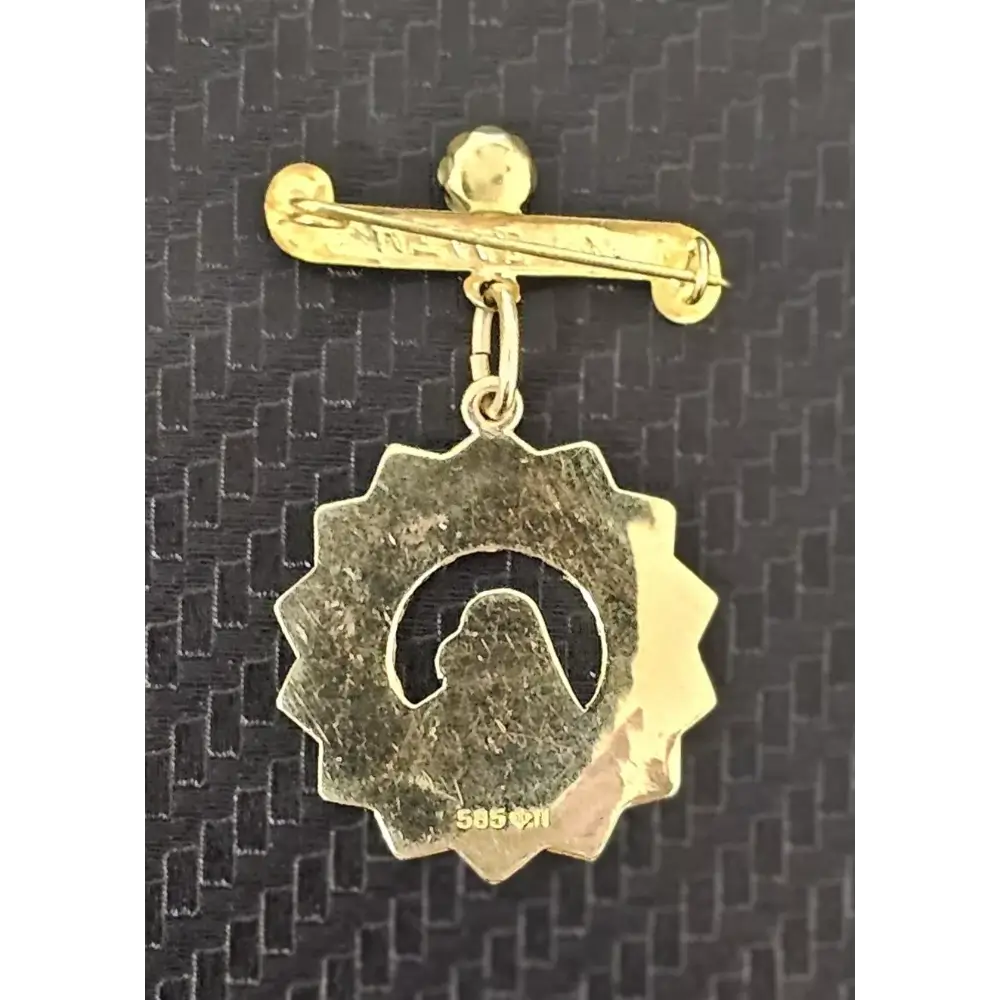 Gold brooch with a circular design on a textured black background