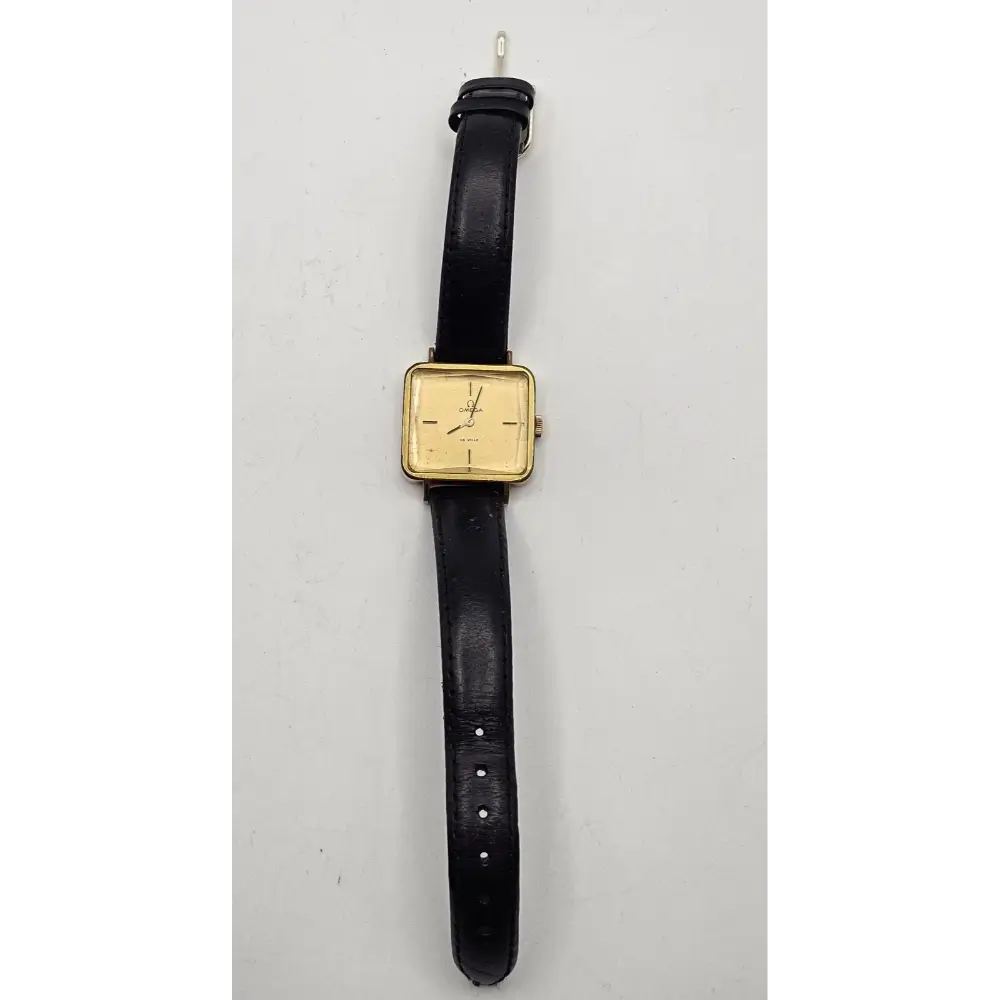 Vintage watch with black strap and gold case on a gray background