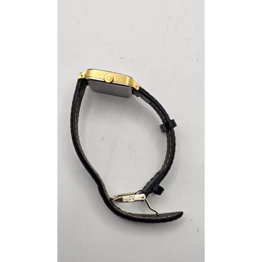 Gold watch with black leather strap on a gray background