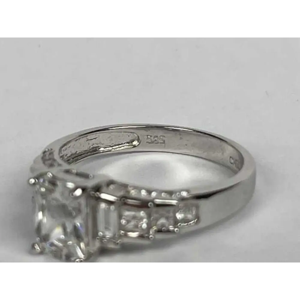 Silver ring with a large diamond and smaller stones on a gray background