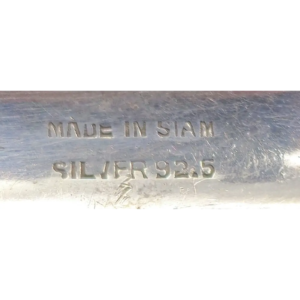 Metallic object with 'MADE IN SIAM' and 'SILVER 925' stamp on a white background