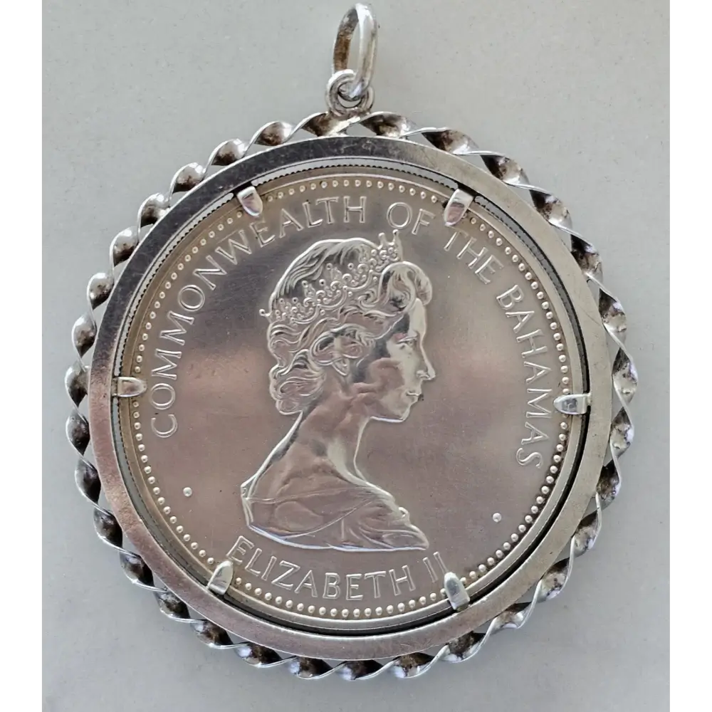 Silver pendant with a profile of a queen and 'Commonwealth of the Bahamas' text on a gray background