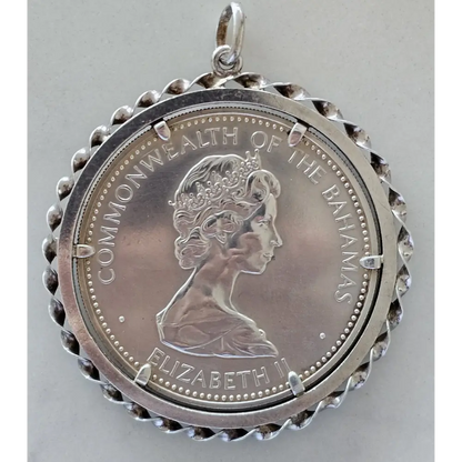 Silver pendant with a profile of a queen and 'Commonwealth of the Bahamas' text on a gray background