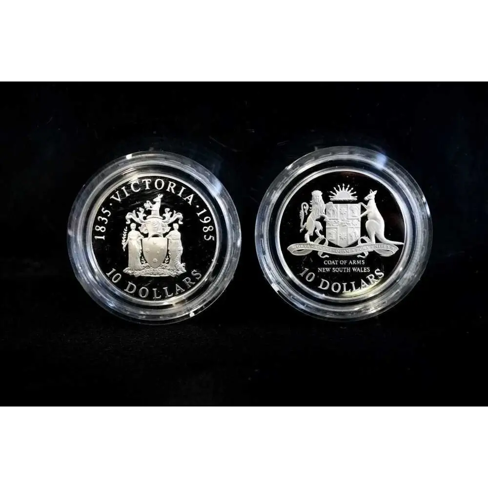 Two silver coins with engraved designs on a black background
