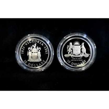 Two silver coins with engraved designs on a black background