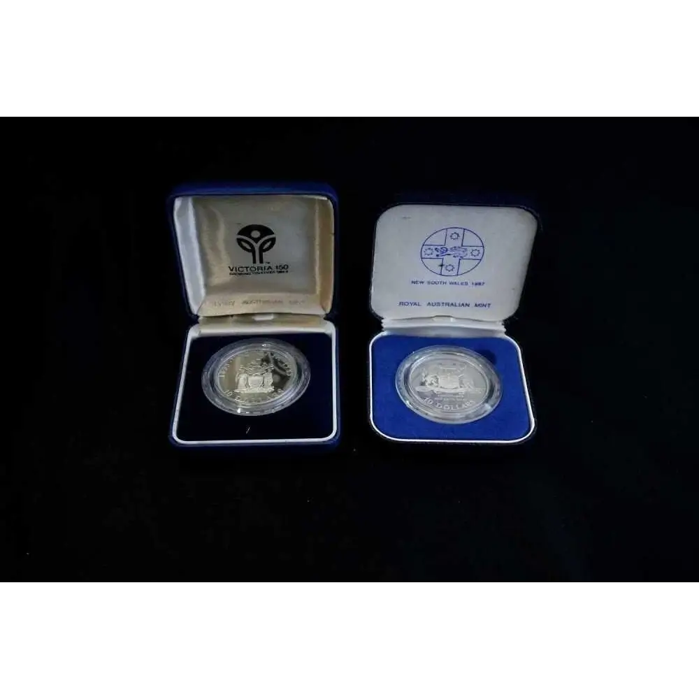 Two silver coins in open display cases on a black background
